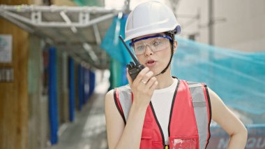 Güzel İspanyol kadın müteahhit sokakta telsizle konuşuyor.