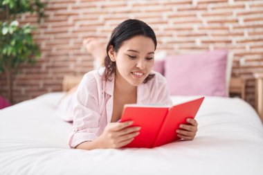 Genç İspanyol kadın yatak odasında kitap okuyor.