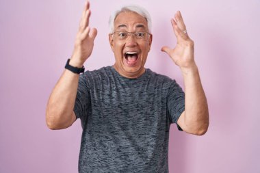 Pembe arka planda duran gri saçlı orta yaşlı bir adam çılgın ve başarıyı kolları açık ve gözleri açık heyecanla haykırarak kutluyor. Kazanan konsept 