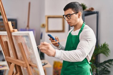 Sanat stüdyosunda akıllı telefon çizimi yapan genç bir sanatçı.