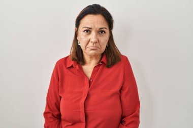 Beyaz arka planda duran Latin kökenli olgun bir kadın depresif ve endişeli, sinirli ve korkmuş bir şekilde ağlıyor. hüzünlü ifade. 