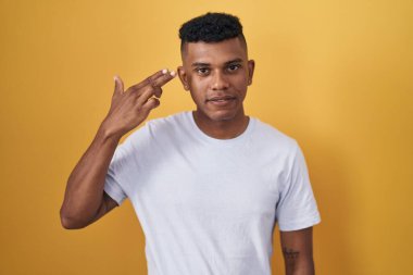 İspanyol asıllı genç adam sarı arka planda durup kendini ve parmaklarını silah gibi havaya kaldırarak vuruyor, intihar ediyor.. 