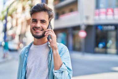 Genç İspanyol adam gülümsüyor. Kendine güveniyor. Sokakta akıllı telefondan konuşuyor.