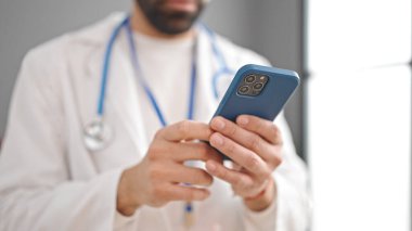 Genç İspanyol doktor klinikte akıllı telefon kullanıyor.