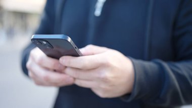 Sokakta akıllı telefon kullanan genç bir Çinli.