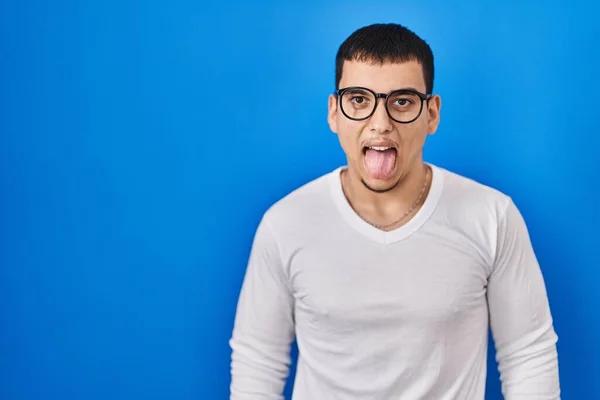 stock image Young arab man wearing casual white shirt and glasses sticking tongue out happy with funny expression. emotion concept. 