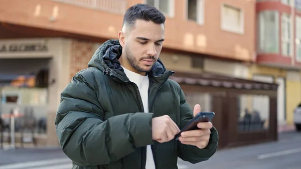 Young Hispanic Man Using Smartphone Serious Expression Coffee Shop Terrace —  Fotos de Stock