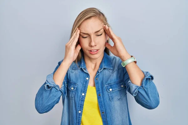 若いブロンドの女性の頭の上に手で青の背景に立って 頭痛の種ので ストレス 片頭痛 — ストック写真