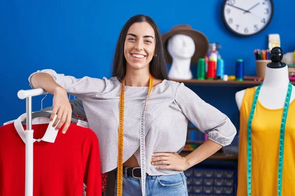 Junge Schöne Hispanische Schneiderin Lächelt Selbstbewusst Kleiderständer Der Bekleidungsfabrik Gelehnt — Stockfoto