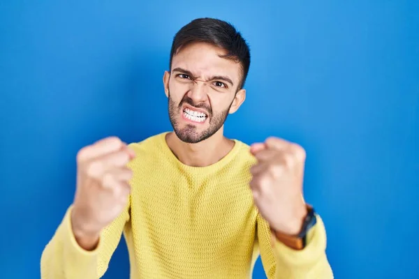 Hispanic Man Standing Blue Background Angry Mad Raising Fists Frustrated —  Fotos de Stock