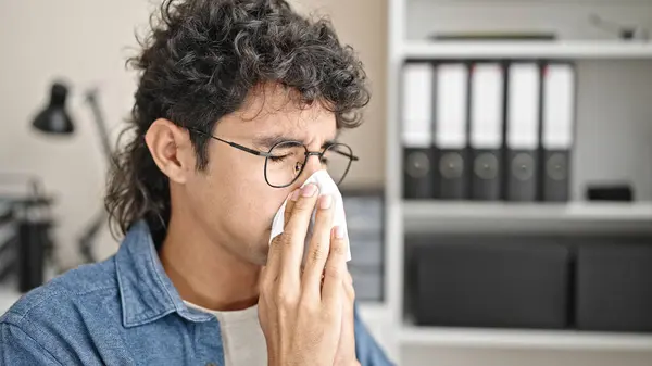 Young hispanic man business worker being sick using napkin at office