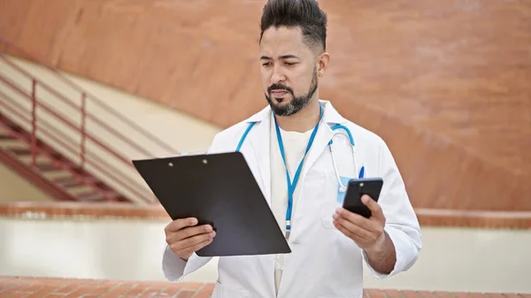 Mladý Latin Muž Lékař Pomocí Smartphone Čtení Dokumentu Nemocnici — Stock fotografie