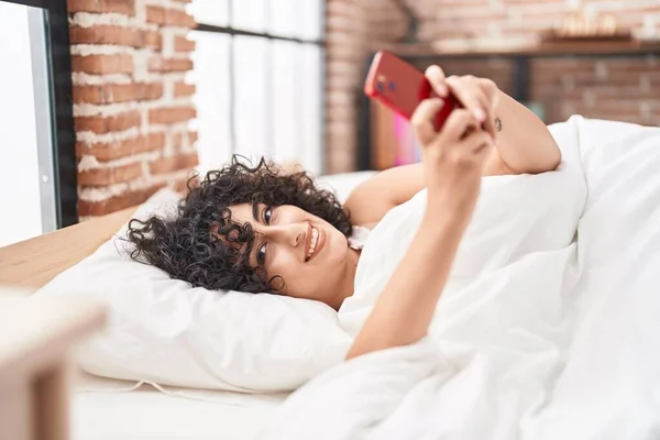 Młoda Kobieta Bliskim Wschodzie Pomocą Smartfona Leżącego Łóżku Sypialni — Zdjęcie stockowe