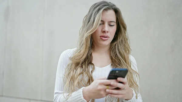 Νεαρή Ξανθιά Γυναίκα Που Χρησιμοποιεί Smartphone Σοβαρή Έκφραση Στο Δρόμο — Φωτογραφία Αρχείου