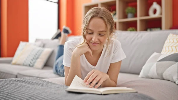 Young Blonde Woman Reading Book Lying Sofa Home — Stock Fotó