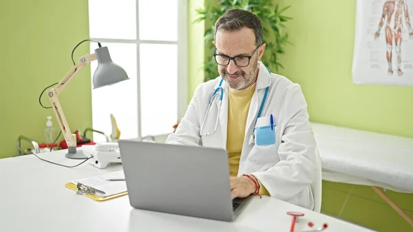 Middle Age Man Doctor Using Laptop Working Clinic — Zdjęcie stockowe