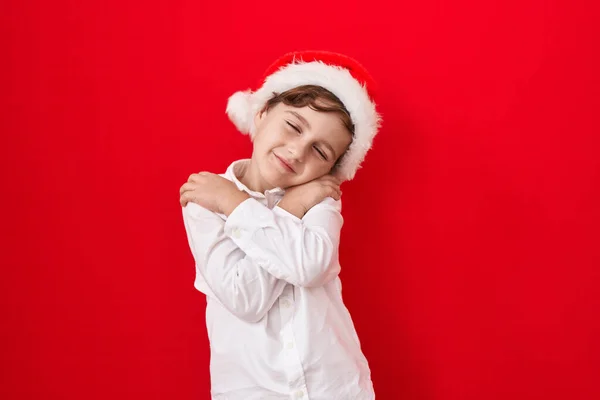 Malý Kavkazský Chlapec Vánočním Kloboukem Červeném Pozadí Objímající Šťastný Pozitivní — Stock fotografie