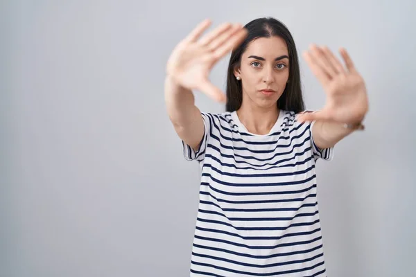 若いですブルネット女性を身に着けていますストライプTシャツは 手の手のひらと指を使用してフレームを行います カメラの視点 — ストック写真