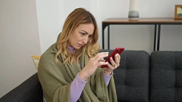 Evdeki Kanepede Oturan Akıllı Telefon Kullanan Battaniyeli Güzel Spanyol Bir — Stok fotoğraf