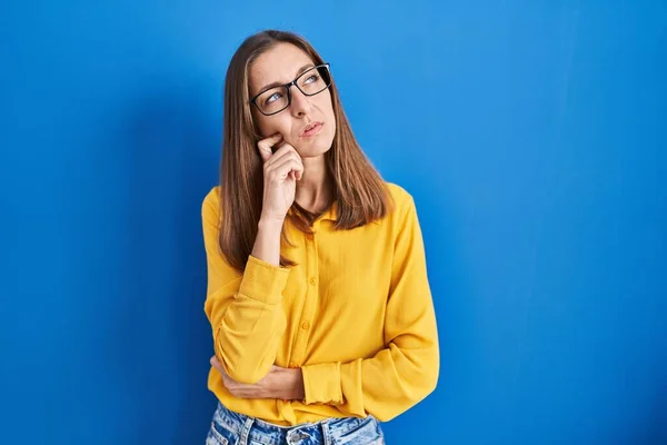 Mujer Joven Con Gafas Pie Sobre Fondo Azul Con Mano —  Fotos de Stock