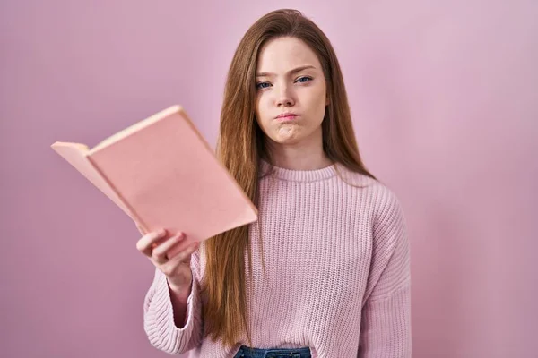 Fiatal Kaukázusi Olvas Egy Könyvet Rózsaszín Háttér Puffadt Arc Vicces — Stock Fotó