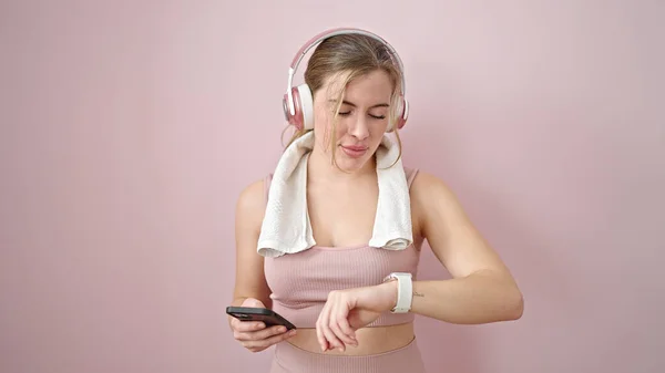 Молодая Блондинка Слушает Музыку Глядя Секундомер Изолированном Розовом Фоне — стоковое фото