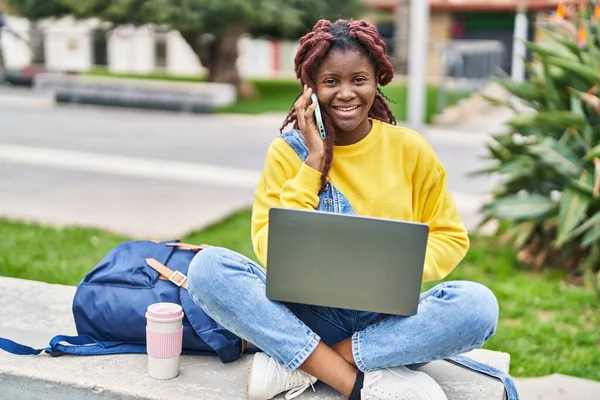 在校园公园用笔记本电脑用智能手机交谈的非洲裔美国女学生 — 图库照片