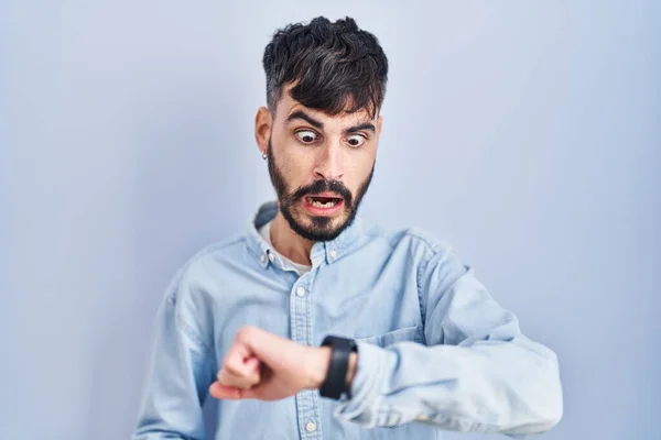Jonge Spaanse Man Met Baard Blauwe Achtergrond Kijkend Naar Horloge — Stockfoto