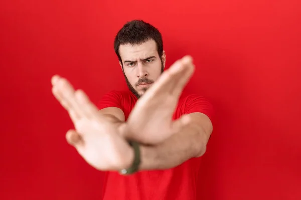 Junger Hispanischer Mann Trägt Lässig Rotes Shirt Ablehnung Ausdruck Verschränkten — Stockfoto