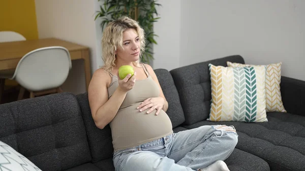 Joven Embarazada Comiendo Manzana Tocando Vientre Casa — Foto de Stock