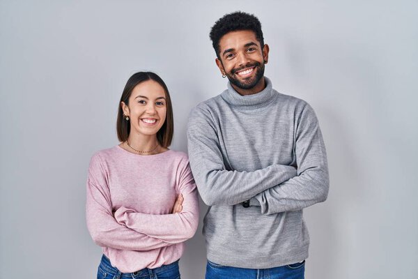Young hispanic couple standing together happy face smiling with crossed arms looking at the camera. positive person. 