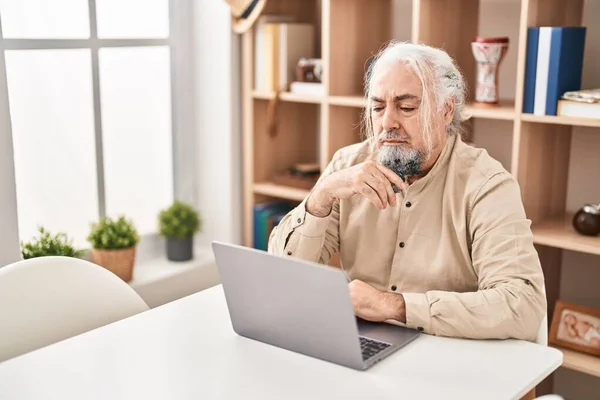 中年白髪の男を使用してノートパソコンを使用してテーブルの上に家に座って — ストック写真