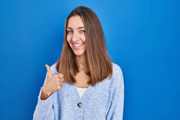 Young Woman Standing Blue Background Doing Happy Thumbs Gesture Hand — Zdjęcie stockowe