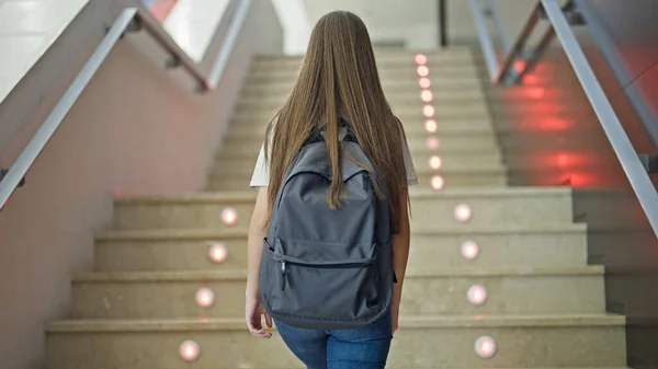 Young beautiful girl student wearing backpack climbing stairs up at school