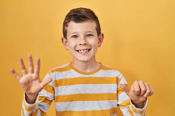 自信と幸せ笑みを浮かべている間 若い白人の子供は黄色の背景の上に立っていると指の数6を指しています — ストック写真