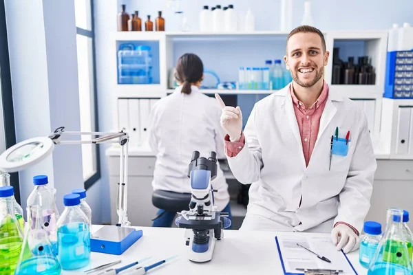 Junger Mann Wissenschaftlichen Labor Lächelt Glücklich Und Zeigt Mit Hand — Stockfoto