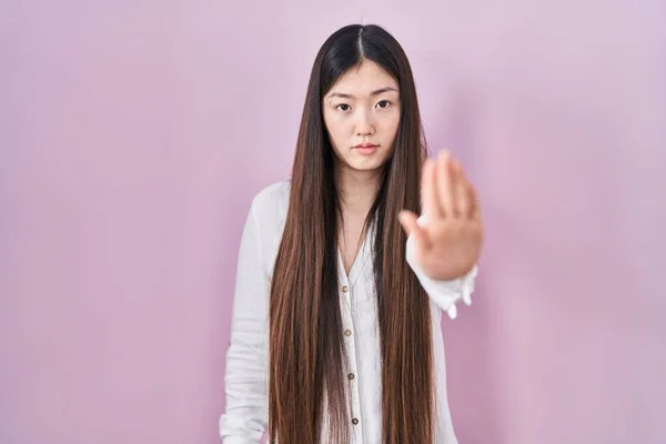 中国年轻女子站在粉红的背景上 不停地用手掌唱歌 用消极而严肃的手势警告人 — 图库照片