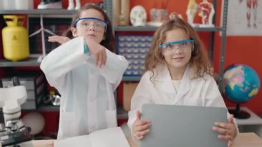 Laboratuar sınıfında kollarını kavuşturmuş sevimli kız öğrenciler.