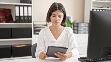 Genç, güzel, İspanyol bir iş adamı ofiste dokunmatik bir düşünce kullanıyor.