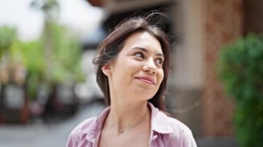 Genç, güzel, İspanyol bir kadın gülümsüyor kendine güveni tam, saçlarını tarıyor.