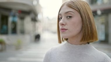 Sokakta ciddi bir ifadeyle duran genç sarışın kadın.