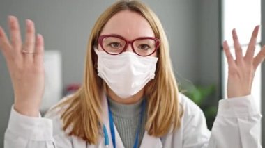 Genç sarışın kadın doktor klinikte maske takarak sinirli ve stresli.