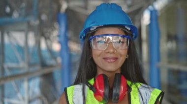 Afro-Amerikalı kadın inşaatçı gülümseyerek sokakta duruyor.