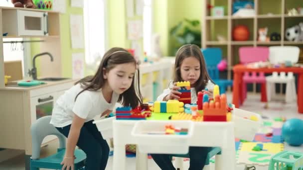 楽しいです女の子遊びます建設ブロックでテーブルの上に座って幼稚園 — ストック動画