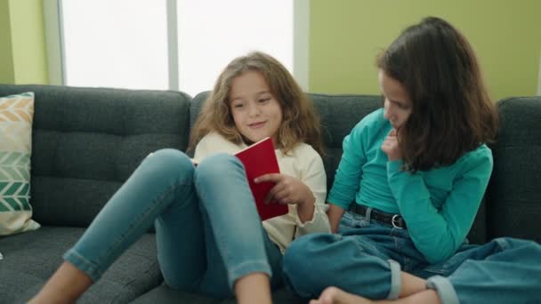 Adorable Girls Reading Book Sitting Sofa Home — Stock Video
