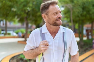 Orta yaşlı bir adam parkın kenarına baktığında kendinden emin gülümsüyor.