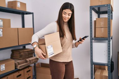 Genç, güzel, İspanyol bir kadın. İş adamı. Ofiste akıllı telefon paketi kullanıyor.