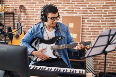 Müzik stüdyosunda elektro gitar çalan genç bir sanatçı.