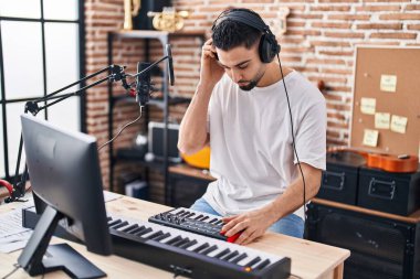 Genç Arap müzisyen müzik stüdyosunda piyano klavyesi çalıyor.