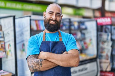 Young bald man waiter smiling confident standing with arms crossed gesture at coffee shop terrace